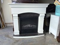 Front view of white wooden mantel electric fireplace with gray granite facing and insert