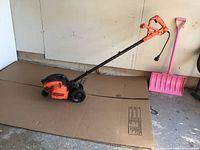 Full view of the Black and Decker electric garden edger showing the handle, wheels, and body from side angle.