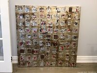 Front view of large abstract canvas painting showing grid of textured squares in metallic bronze, black, red, and silver.