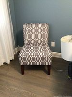 Front view of grey and white patterned occasional chair, showing geometric upholstery and wooden legs.