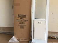 New Ideal Pet-Fit aluminum pet door in white aluminum frame shown next to box with product details visible