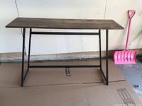 Front angle view of sofa table showing wood veneer top and black metal legs.