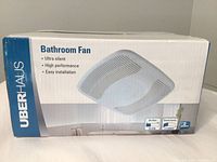 Front side of the unopened box showing Uberhaus branding, Bathroom Fan text, features such as ultra silent, high performance, and easy installation, and product image of the fan grille.