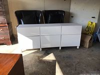 Front view of the white high-gloss dresser showing six drawers and overall shape in garage setting.