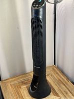 Front angle view of the black Honeywell tower fan showing tall slim body, air vent grille, and controls on top.