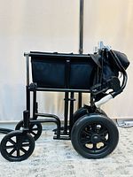 Folded black Airgo transport wheelchair showing side profile including wheels and frame