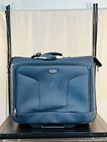 Front view of Ricardo Beverly Hills blue rolling tote luggage bag with padded front panel and logo.