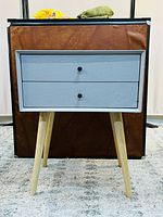 Front view of white side table with two drawers and natural wooden legs.