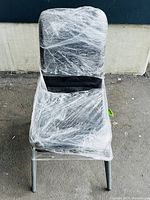 Front view of a black velvet dining or study chair wrapped in protective plastic.