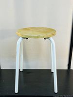 Front view of vintage stackable stool showing round wood seat and white metal legs