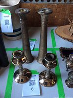 Four candlesticks shown: two tall matte pewter with simple tapering design (about 10 inches), two shorter polished pewter with rounded base and decorative stem (about 6 inches).