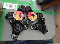 Four black metal 3-wheel caster sets with labels showing 6 inches, stacked on table.