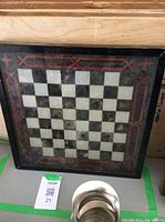 Chess board table top with alternating black and white squares and red decorative border.