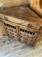 Front view showing the triangular top, single drawer, and double doors with vertical spindle details.