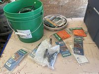 Green bucket with coiled drip tubing and irrigation accessories in packaging on a tabletop.