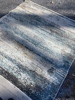 Photo showing the textured abstract rug pattern blending blue, grey and beige in natural light.