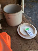 Beige stone crock with lid off, showing interior and crown emblem on front.