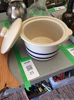 Stoneware crock open with lid leaning on the side showing interior and exterior detail.