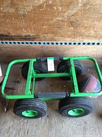 Green metal utility trolley with four large pneumatic tires, viewed from above showing tire hubs and frame.