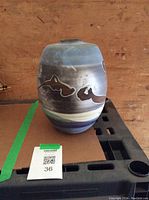 Full side view of the ceramic vase showing blue, gray, and brown abstract painted motifs.