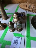 Pair of vintage silver salt and pepper shakers with visible aged patina and a small ornate silver sugar dish with a blue glass liner and small spoon.