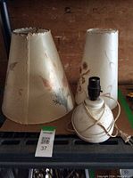 Two floral print lamp shades and vintage white ceramic lamp base with electrical cord, showing wear and vintage condition.