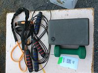 Two jump ropes, one green dumbbell, and one Lululemon yoga block placed on white surface