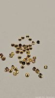 Top-down view of a collection of small, round, golden yellow sapphire gemstones scattered on a neutral background.