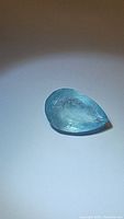 Top view of natural pear-shaped aquamarine, showing blue color and surface reflections