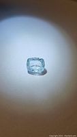 Close-up front view of the light blue cushion cut aquamarine gemstone showing clarity and inclusions under focused light.