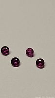Four natural rubies in deep fuchsia pink-purple, round cabochon cut viewed on light background to show color and clarity