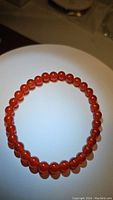 Photo of natural fire orange carnelian stretched loop bracelet with polished round beads approximately 6mm in size.