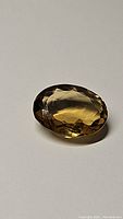 Photo of oval cut golden champagne citrine gemstone showing its size, cut facets, and amber color.