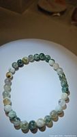 Top-down view of natural tree agate stretchy bracelet laid flat, showing bead details and color variations.