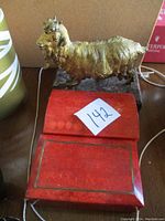 Gold gilt ram on dark marble base with one foot loose, two red coral boxes below
