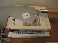 Stack of historical Belleville books and a metal trowel on top with a lot number sticker.