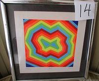 Photo showing the colorful geometric limited edition print with rainbow concentric shapes, framed in metallic frame with dark matting. Visible artist signature 'Harkaj' and edition number 237/400 below print.