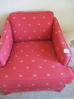 Front view of the red Mid-Century Modern style chair with rooster pattern upholstery, showing cushioned seat and back with fitted skirt.