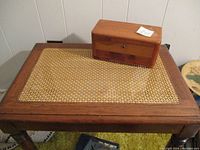 Side table top with cane inset and small cedar sample trunk placed on it