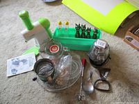 Lot overview showing yogurt maker, glass dish, black cat shaped salt and pepper shakers in green tray, decorative spoons, and other utensils