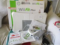 Nintendo Wii console lot with Wii Fit Plus balance board, games, controller, sensor bar, power adapter, and manuals.