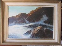 Full view of the framed oil painting showing a coastal rocky scene with waves crashing and birds flying.