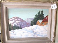 Full view of the framed painting showing mountain cabin, snow, and pine trees, with signature visible on bottom left.