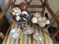 Overall lot setup showing two silver plated pedestal trays holding decorative balls and two silver plated covered dishes placed in front.