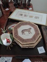Five stacked octagonal ceramic plates with animal print design, bamboo-style textured rims alongside decorative chicken container and wooden plaque with cottage painting.