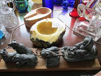 Metal sculpture of indigenous person on dog sled with four dogs, shown from an angle with various glassware in background