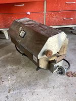 Full view of the portable propane boat BBQ showing stainless steel housing with wooden side handle and propane regulator at the base.
