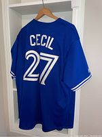 Back view of the blue jersey showing 'CECIL' name and '27' number printed in white with black outlines.