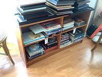 Front view of bookshelf partially filled with books and magazines on bottom open shelves and black top surface.