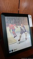Framed autographed photo showing Eddie Shack in Maple Leafs uniform on the ice near the net.